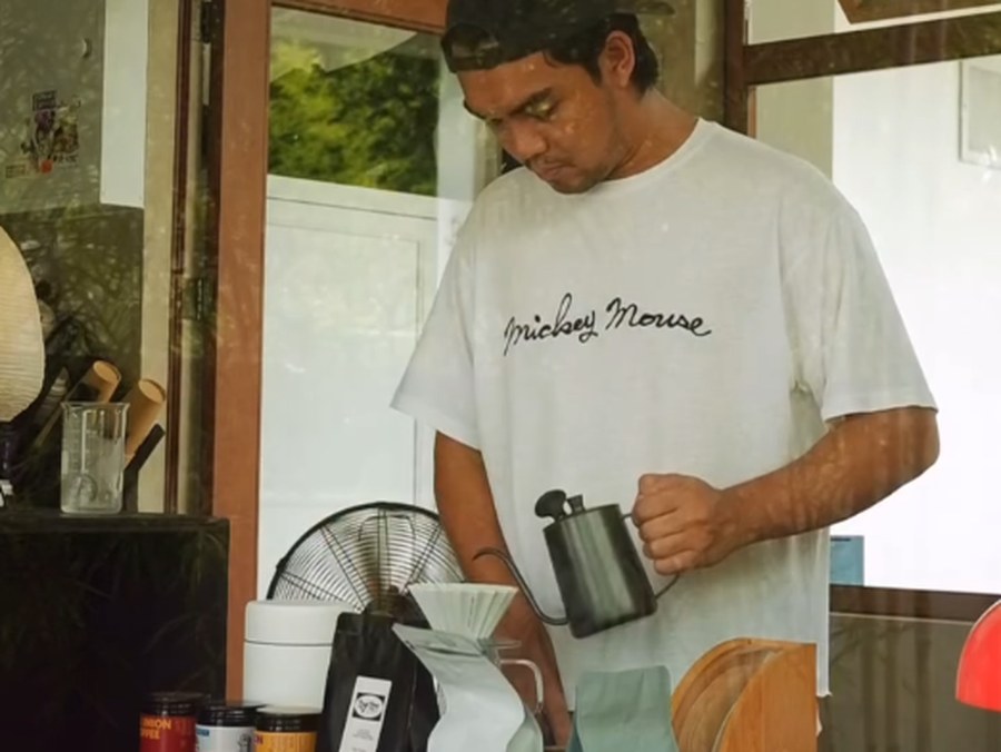 The cafe owner pouring from a gooseneck kettle into a V60